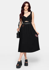 Woman wearing a black dress with cut-out design and embroidered details on a white background