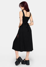 Woman wearing a black dress with a tie waist on a white background