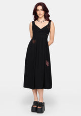 Woman wearing a black dress with cut-out design and embroidered details on a white background