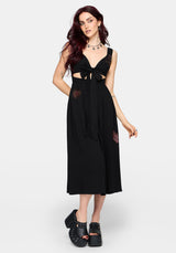 Woman wearing a black dress with cut-out design and embroidered details on a white background