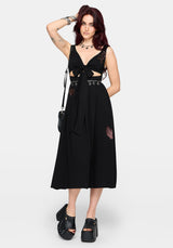 Woman wearing a black dress with cut-out design and embroidered details on a white background