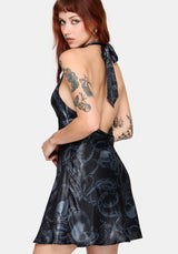 Woman wearing a black satin snake printed mini dress with an open back against a white background