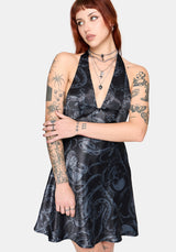 Woman wearing a black satin snake printed mini dress against a white background