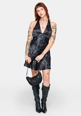 Woman wearing a black satin snake printed mini dress against a white background
