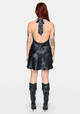 Woman wearing a black satin snake printed mini dress with an open back design against a white background