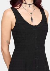 Black sleeveless dress with button details on a plain background