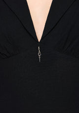 Close-up of a black dress with a charm zipper detail.