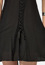 Black mini dress with intricate lace detailing on a white background