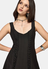 Woman wearing a black mini dress with lace details on a white background
