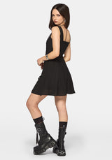 Woman wearing a black mini dress and black boots on a white background