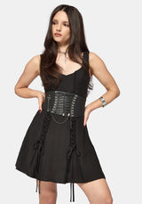 Woman wearing a mini black lace-up dress on a white background