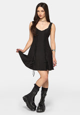 Woman wearing a black dress with lace-up front and black boots on a white background