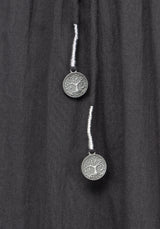 Close up detail of two silver pendants on a grey midi dress