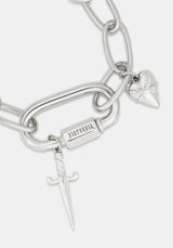 A close-up of a silver-toned chain bracelet featuring a large open-link chain, a rectangular bar engraved with 'DISTURBIA', a small dagger charm, and a heart-shaped charm with a rose engraving, on a light gray background.