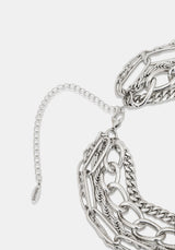 Close-up of a silver-toned chunky chain necklace with layered links and an adjustable extender chain on a light gray background.