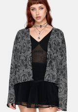 Woman wearing a black patterned cardigan over a black outfit on a white background