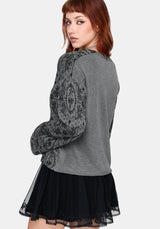 Woman wearing a black patterned cardigan over a black outfit on a white background