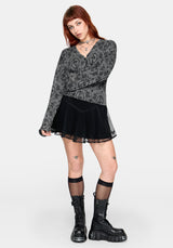 Woman wearing a black patterned cardigan over a black outfit on a white background