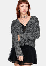 Woman wearing a black patterned cardigan over a black top and skirt on a white background
