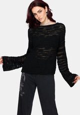 Woman wearing a black distressed jumper with long sleeves and back denim jeans on a white background