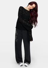 Woman wearing a black distressed jumper with long sleeves and back denim jeans on a white background