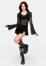 Woman wearing a black lace mesh top with long sleeves on a plain background
