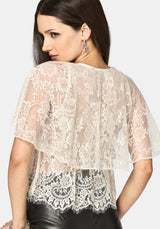 Woman wearing a cream tiered lace top against a white background