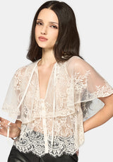 Woman wearing a cream lace top against a plain background