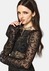 Woman wearing a black mesh long sleeve top against a white background
