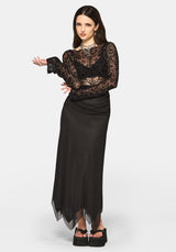 Woman wearing a black long sleeve top and black maxi skirt on a white background
