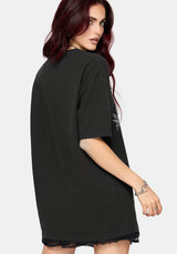A woman modeling an oversized black t-shirt with a large white graphic print of a coiled snake and floral elements on the front, set against a plain light gray background.