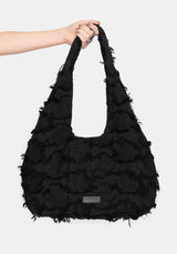 Black ruffled handbag held by a person against a white background