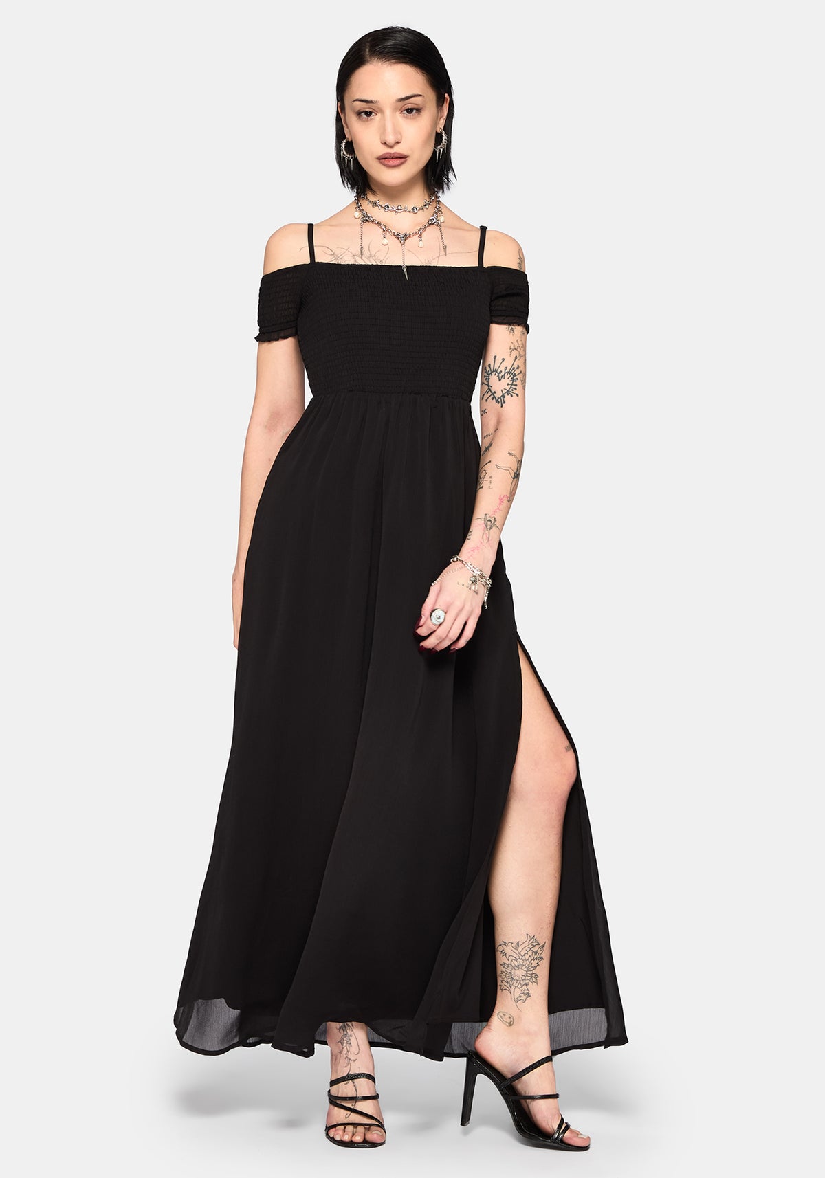 Woman wearing a black off-shoulder maxi dress with a thigh slit on a white background