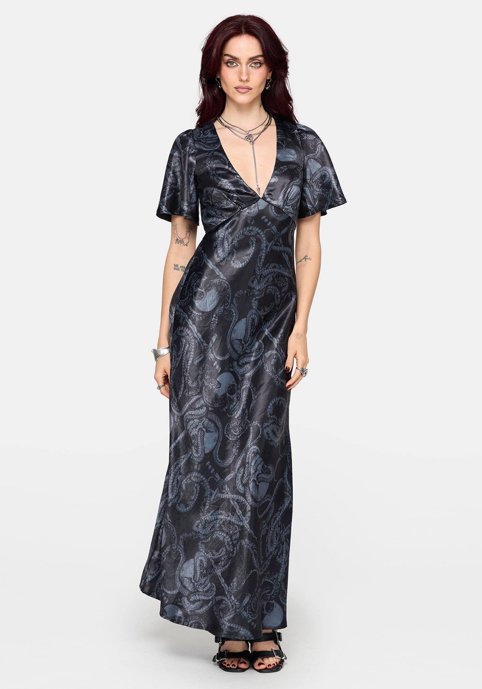 Woman wearing a black maxi satin snake printed dress on a white background