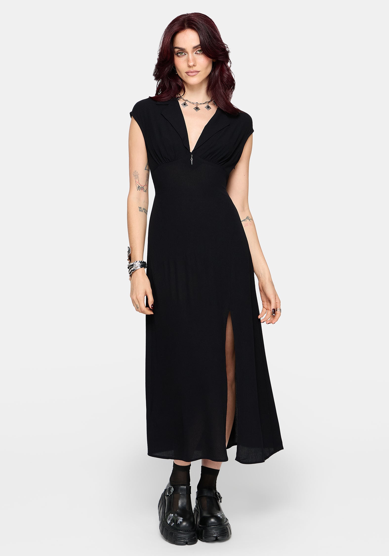 Woman wearing a black dress with a slit on a white background