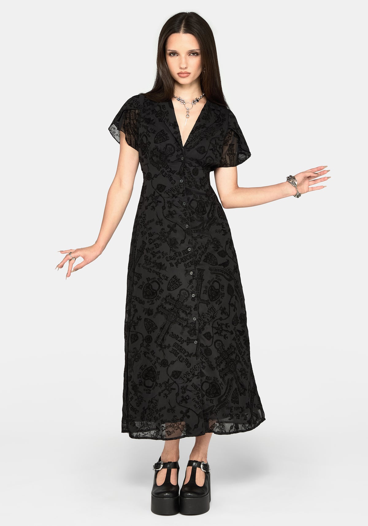 A woman modeling a black midi dress with a subtle tonal floral jacquard pattern, sheer flutter sleeves, and a button-up front, set against a plain light gray background.
