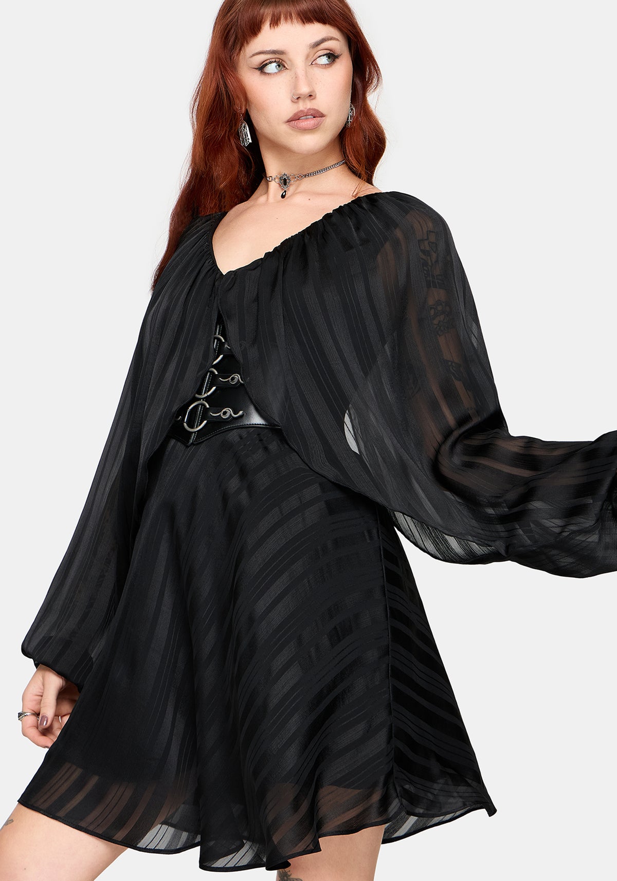 Woman wearing a black dress with sheer sleeves on a white background