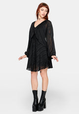 Woman wearing a black dress with sheer sleeves on a white background