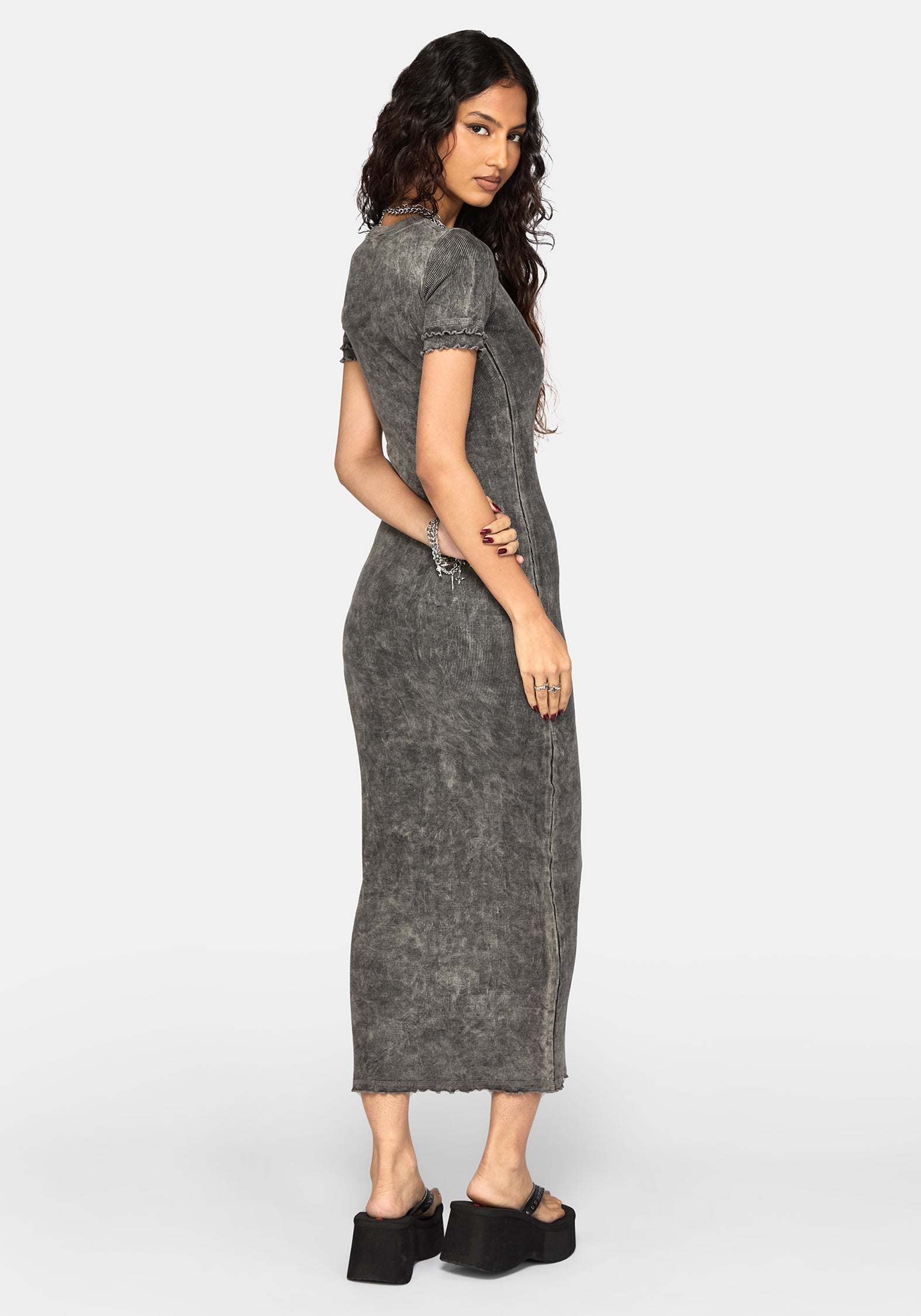 A woman modeling a short-sleeve, knee-length grey dress with a textured, washed finish, shown from a side-back angle against a light gray studio background.