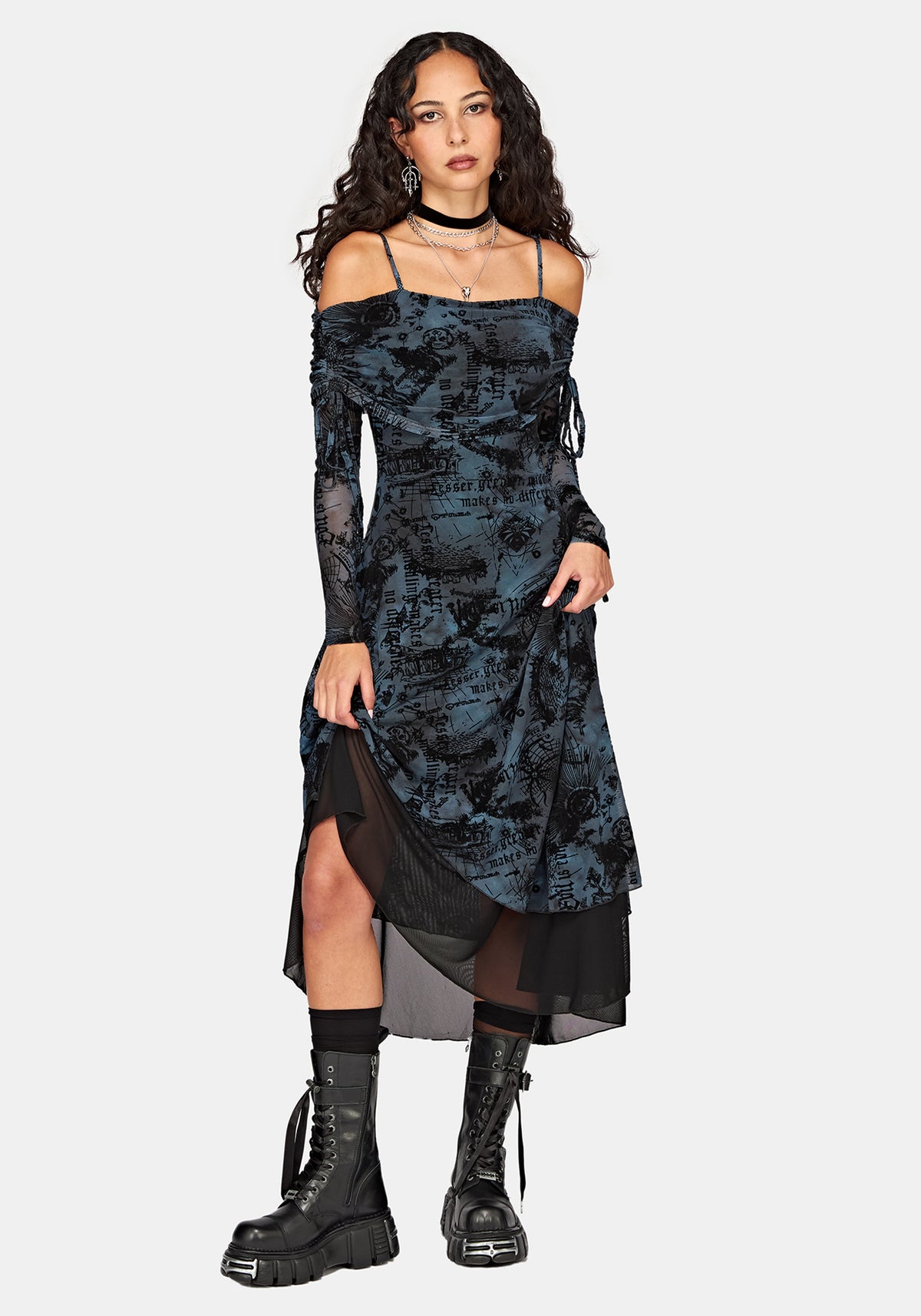 A model wearing a dark blue and black patterned off-the-shoulder midi dress with sheer long sleeves, a high-low hemline, and black lace-up combat boots, set against a solid light gray background.