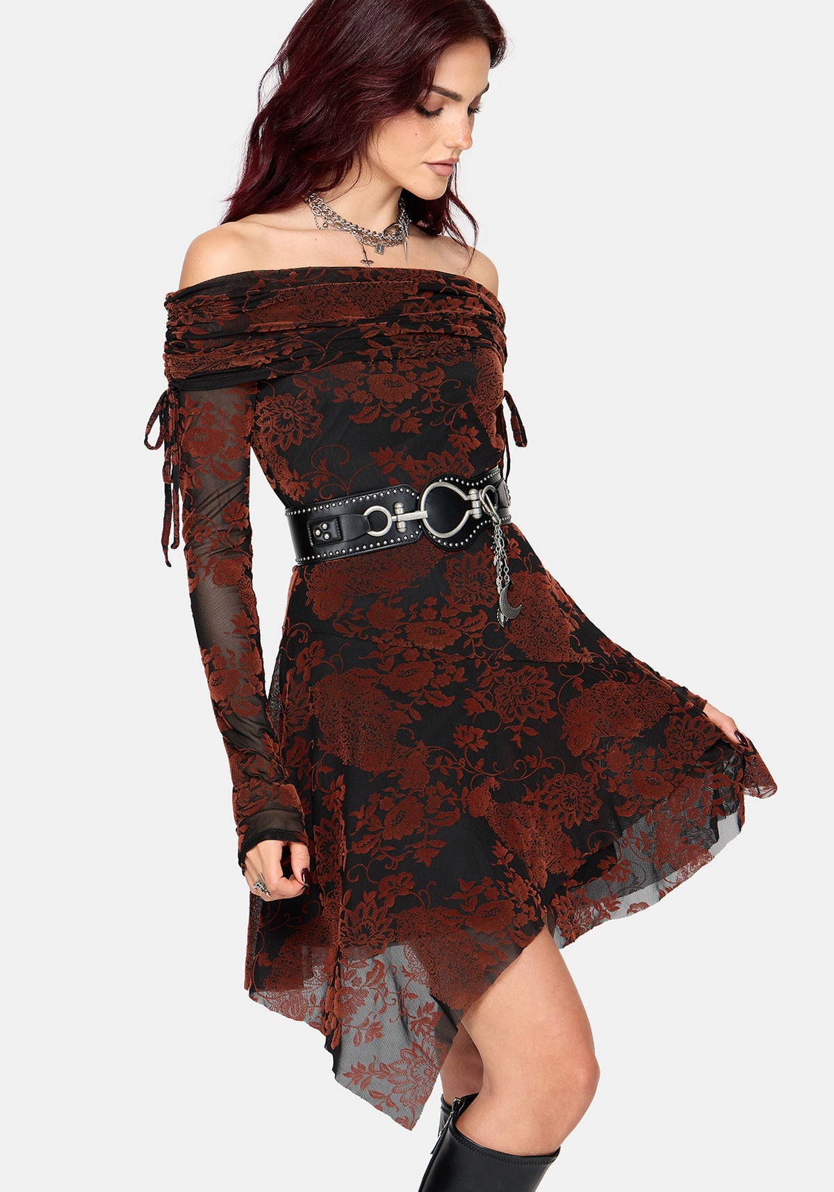 A woman modeling an off-the-shoulder gothic-style dress with a black and dark red floral lace overlay and sheer dark red lining, accessorized with a wide black belt featuring silver hardware.