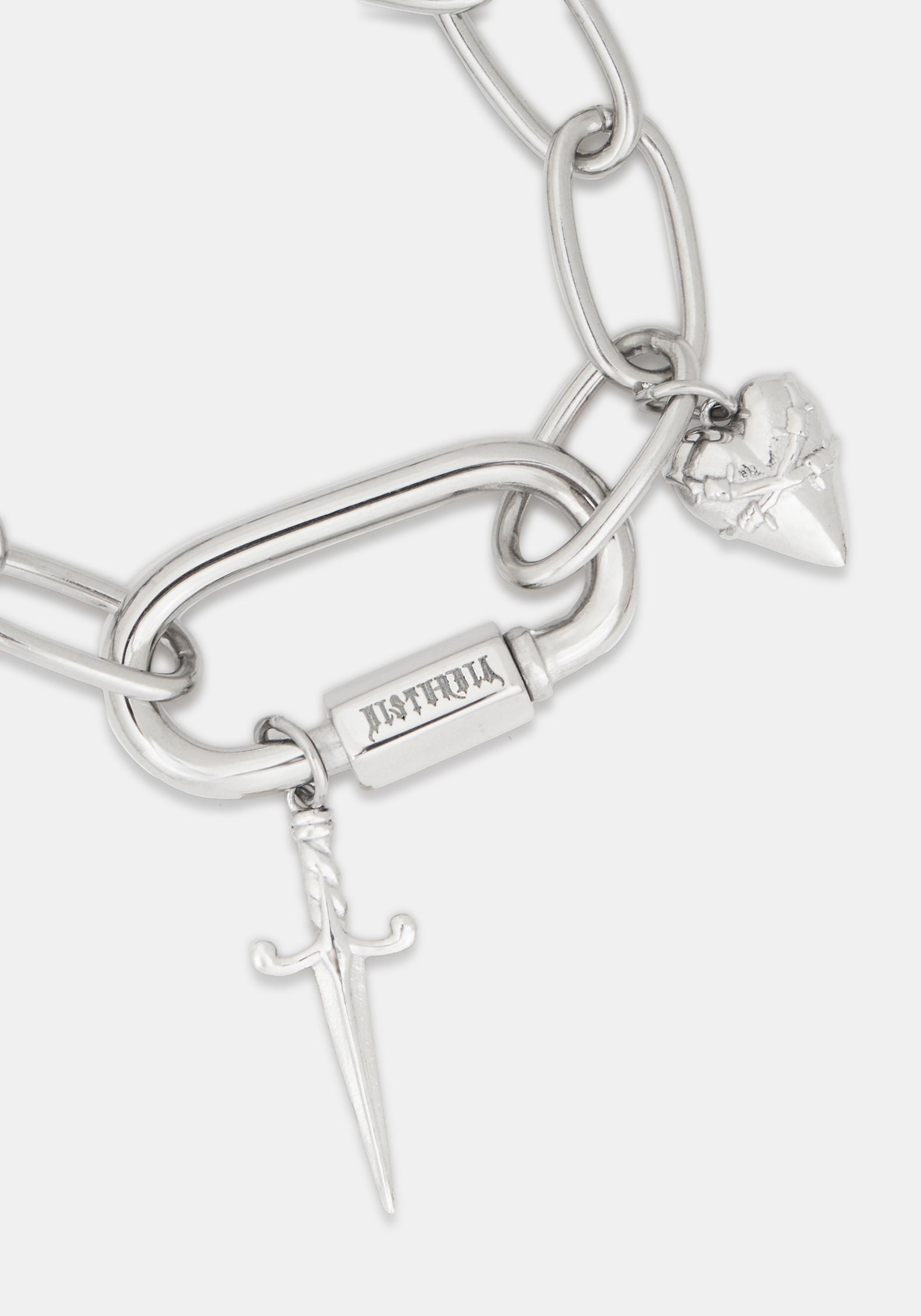 A close-up of a silver-toned chain bracelet featuring a large open-link chain, a rectangular bar engraved with 'DISTURBIA', a small dagger charm, and a heart-shaped charm with a rose engraving, on a light gray background.