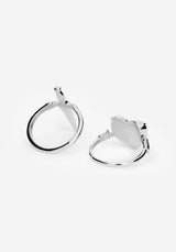 A pair of polished silver rings with heart and sword designs on the front and center of both rings against a white studio backdrop