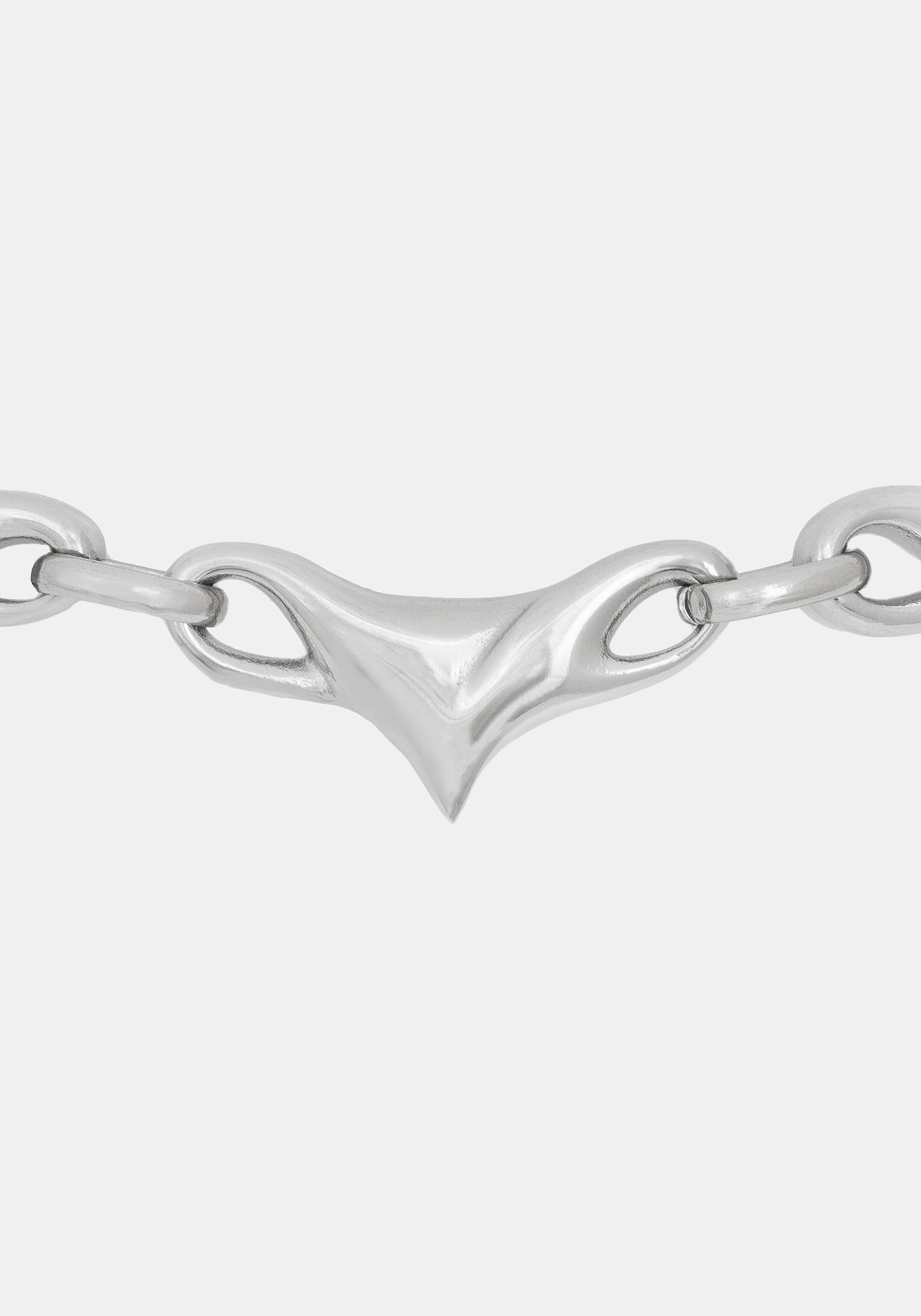 A close-up of a polished silver chain necklace featuring a distinctive central triangular clasp with looped details, set against a solid light gray background.