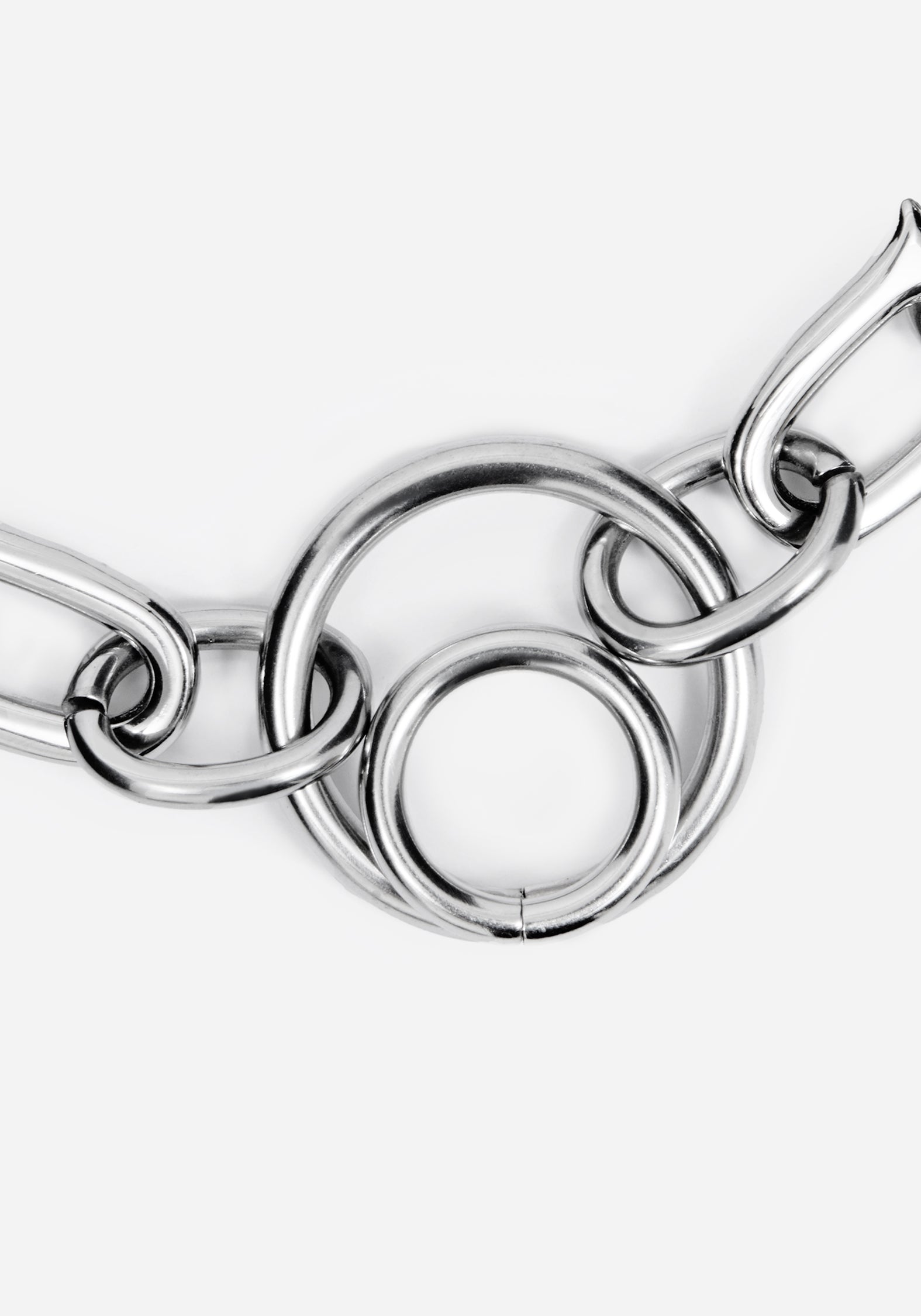 A close-up of a polished silver-toned metal chain with interlocking circular and elongated links on a plain light gray background.