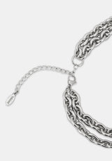 A close-up of a silver-toned chunky chain necklace with a layered double-strand design, an adjustable lobster clasp, and a small branded Disturbia logo on a light gray background.