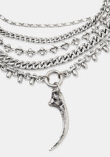 A layered silver-tone chain necklace featuring multiple textured chains, small skull-shaped links, and a curved claw or fang pendant, shown on a light gray background.