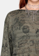 Woman wearing a dark green shirt with zodiac symbol pattern and silver chain necklace.