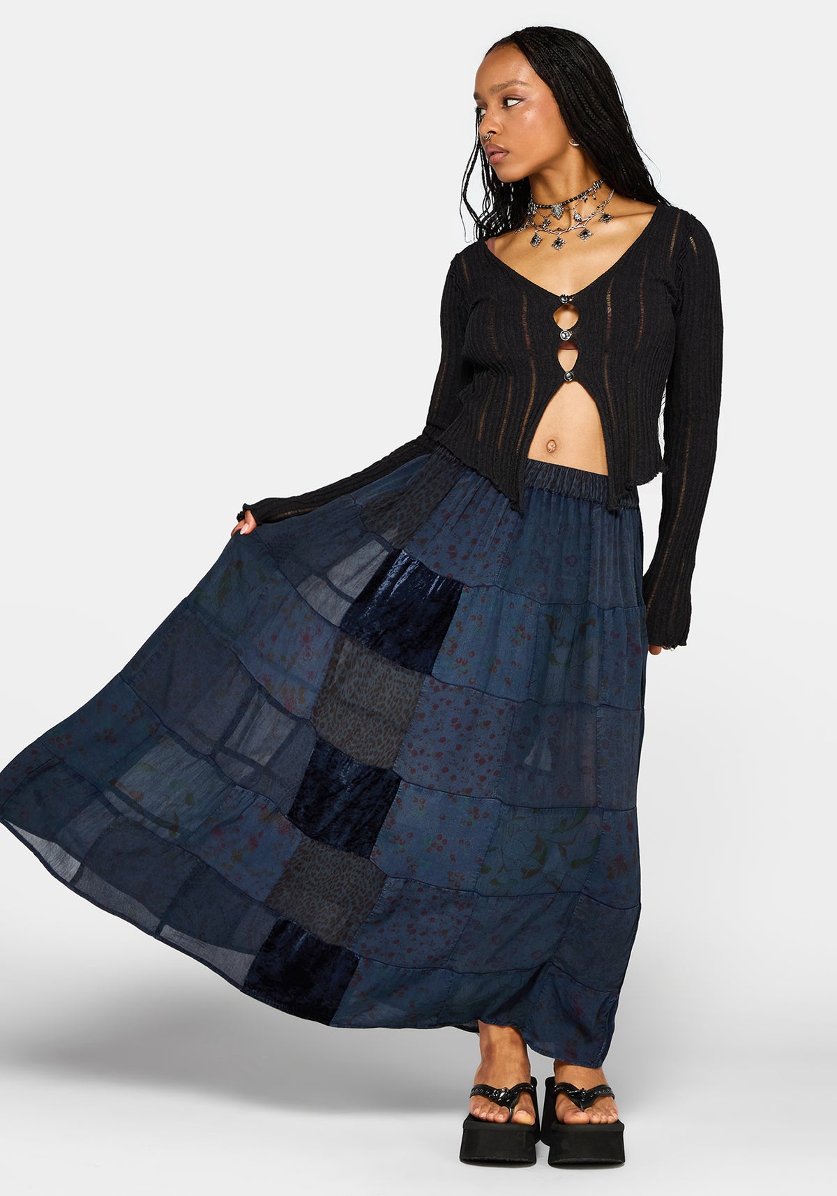 Woman wearing a black top and long navy plaid skirt on a white background