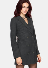 A woman wearing a dark charcoal gray double-breasted pinstripe blazer dress, shown from the waist up against a light gray studio background.